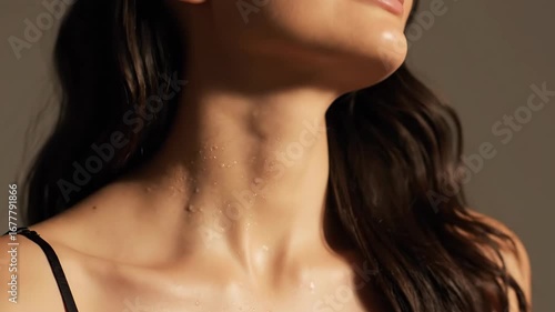 A woman applies fragrance to her neck, dark hair framing skin