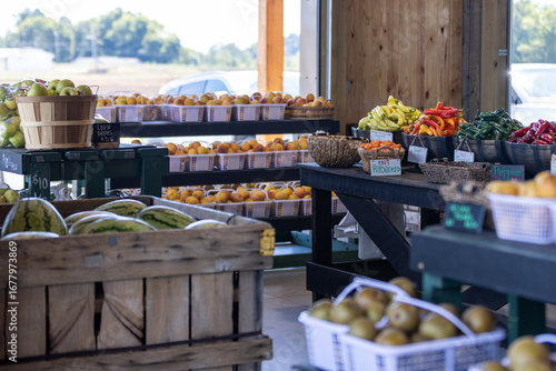 Fresh fruits and vegetables at a farmers market. Watermelons, peaches, peppers, and other produce displayed in baskets and crates.