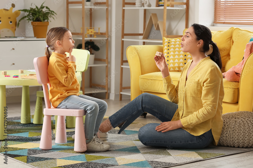 © Pixel-Shot - Female speech therapist with cute little girl pronouncing letters in office
