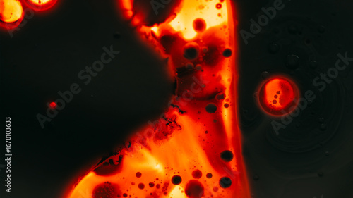 Paint droplet. Spill ink texture. Defocused dark orange red glowing neon water liquid oil bubble flowing fluid on black abstract art light background.