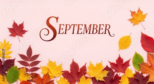 September text with colorful autumn leaves scattered on a light pink background in a flat lay design