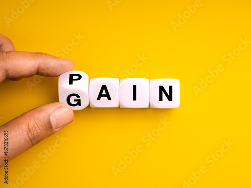 Billede på lærred Hand flipping dice from pain to gain on yellow background symbolizes personal growth, mindset shift, overcoming challenges, success through effort, motivation, and positive change in business or life