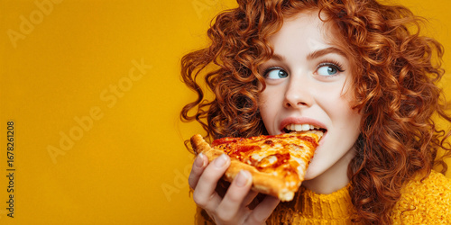 Redhead woman enjoying a slice of pizza on yellow background