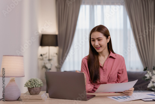 Free Download Young Asian business woman attending online conference meeting, discussing with colleagues remotely via video call on laptop computer, holding financial document, working from home - GFXLoad