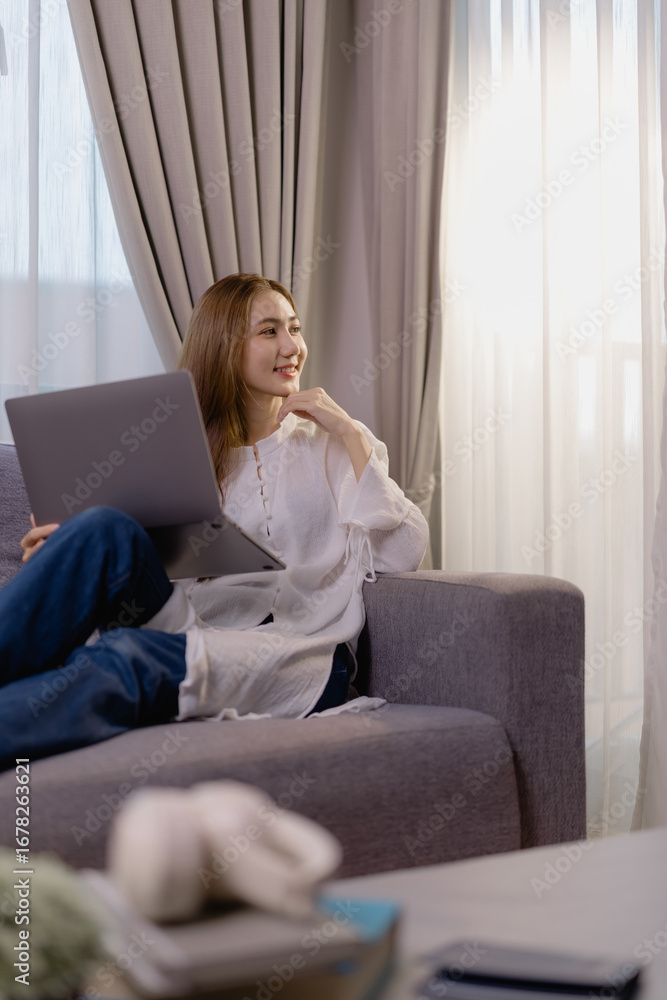 Obraz premium Happy freelancer working from home, taking a break from work and looking out the window, enjoying the natural light and peaceful atmosphere