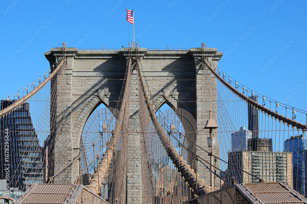 Obraz premium waving american flag above the pillars of the brooklyn bridge a symbol of new york city