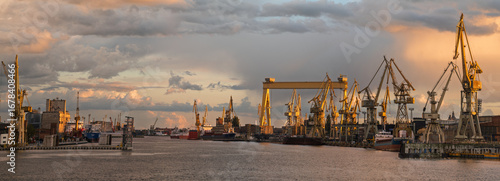 Obraz na plátně Beautiful storm clouds illuminated by the setting sun over the shipyard in Szcze