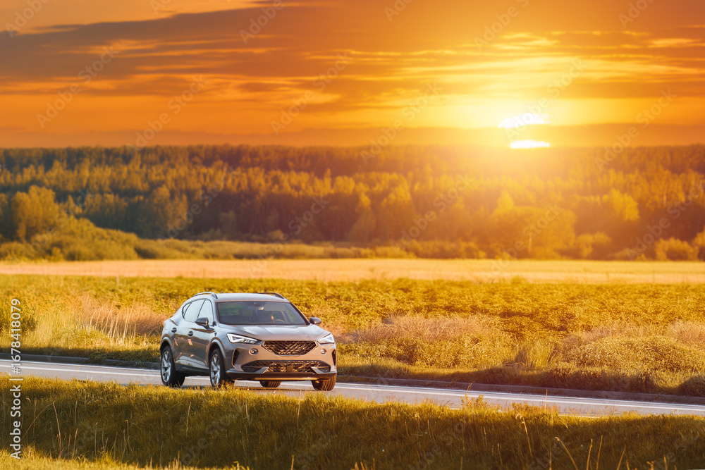 Fototapeta premium Luxury SUV on a scenic road during a beautiful sunset