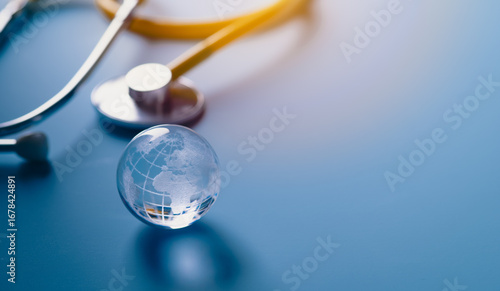 Glass global and stethoscope on light blue background, earth day, world health day, medical and healthcare business technology concept