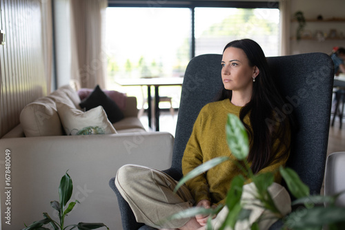 Canvas Print Depressed woman sitting in armchair and staaring at nothing.