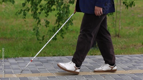 Blind man walking on tactile paving using white cane