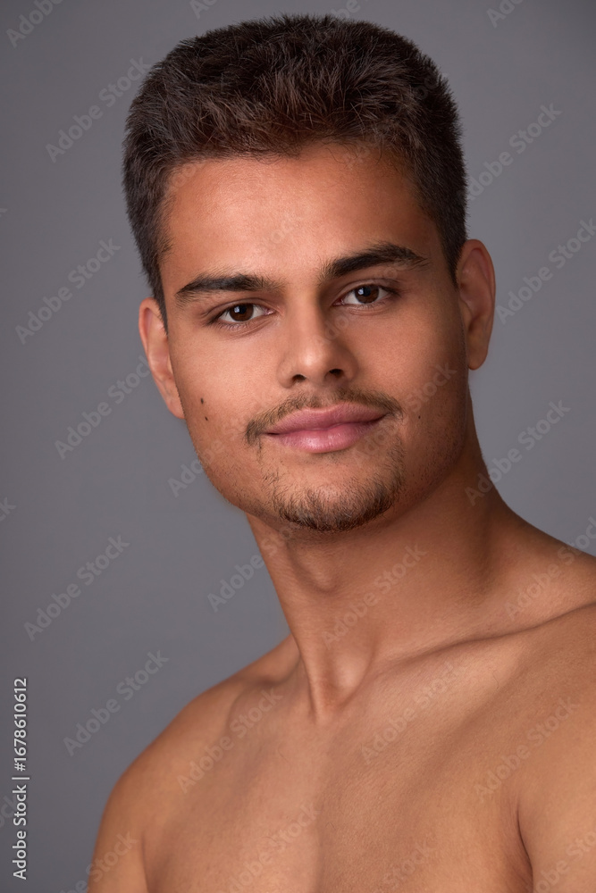Obraz premium Portrait of an attractive young brunette with a short haircut and light stubble on a gray background