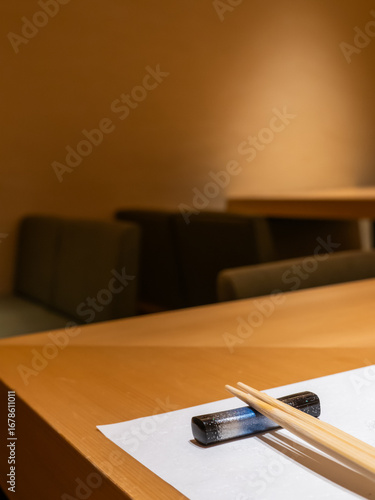 A cozy fine dining table set with chopsticks, hashioki and a simple mulberry paper placemat, creating a warm traditional and inviting atmosphere for a Japanese meal in omakase restaurant