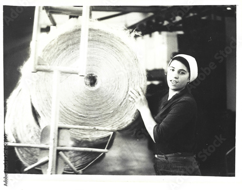 Black and white analog photo of a young woman working near a jute loom at the Odessa Jute Factory, early 1980s Ukrainian SSR, industrial atmosphere