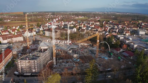 An aerial view of a large-scale residential construction site in Stein, near Nuremberg, Germany. Multiple tower cranes work on new apartment buildings, symbolizing economic growth and the housing boom