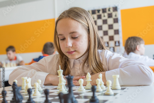 Attractive school kid on chess lesson at school. Smart child girl portrait