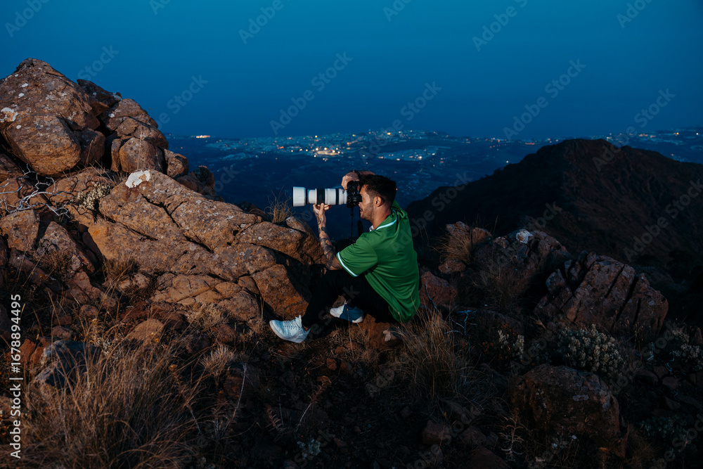 Fototapeta premium Photographer with Telephoto Lens Shooting at Mountain Sunset