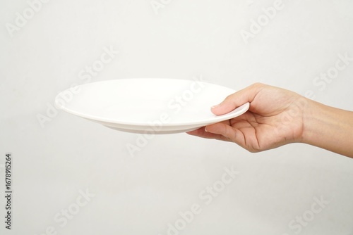 Woman's hand holding an empty plate isolated on white background