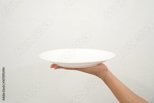 Woman's hand holding an empty plate isolated on white background