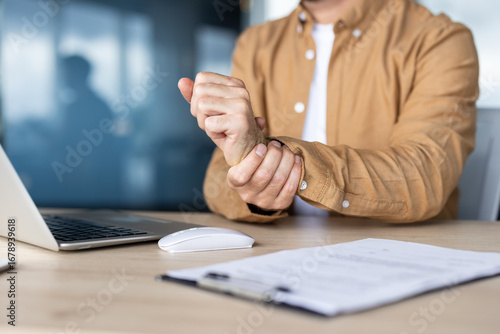 Photos Office worker experiencing wrist pain while working on laptop