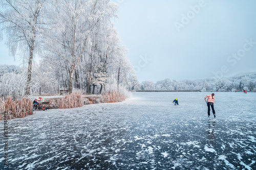 Winter fun as a pair of kids glide on the icy pond, enjoying hockey in a snowy wonderland