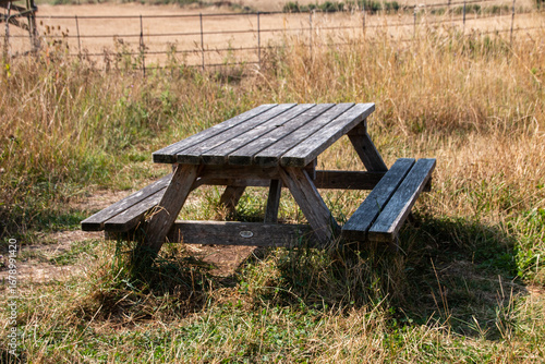 A view of a wooden bench in the middle oif a grass field
