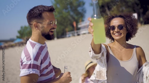 Group of friends having fun at a beach day party. They are dancing, laughing, and drinking cocktails under the sun.