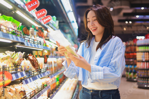 Asian woman shopping in supermarket, smiling and choosing healthy groceries ,Lifestyle concept of consumer behavior in modern retail market