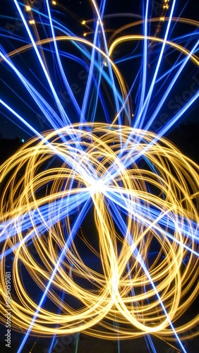 A vibrant display of swirling, light-painted lines in bold blue and gold hues, creating an abstract, dynamic composition against a dark background.