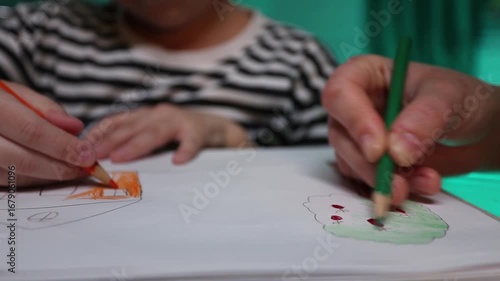 child and adult draw with pencil on a piece of paper