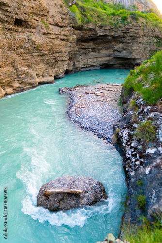 Turquoise mountain river with rapids flowing between cliffs, top view of gorge and rocks.