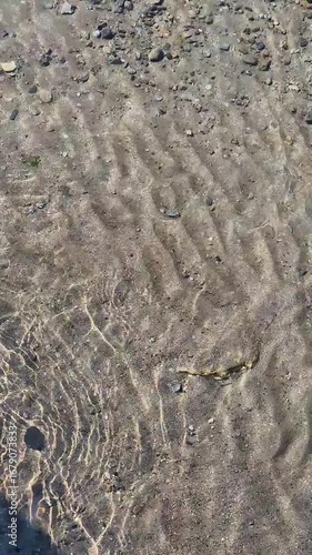 Pristine mountain water with visible sediments, sparkling in natural light.