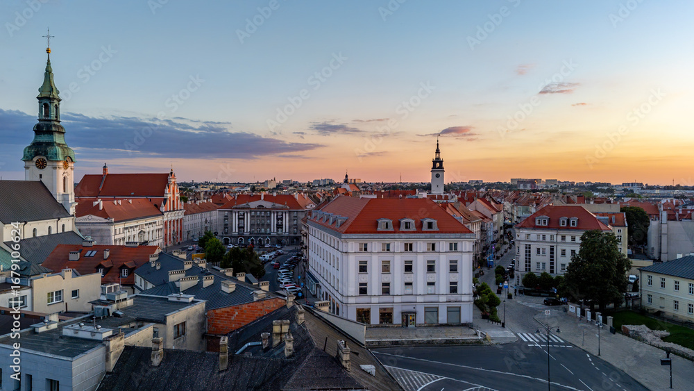 Naklejka premium Sunset panorama of Kalisz, view of St. Joseph’s Church and town hall in the distance, red rooftops of townhouses, historic city center skyline.