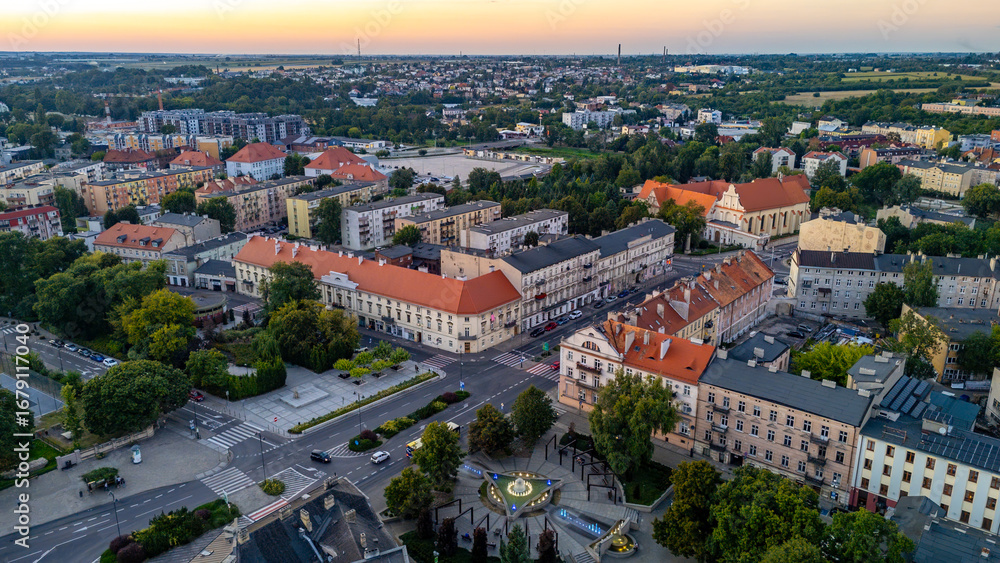 Fototapeta premium Sunset aerial panorama of Kalisz, view of “Nights and Days” fountain square, historic townhouses, streets and landmark buildings in the city center.