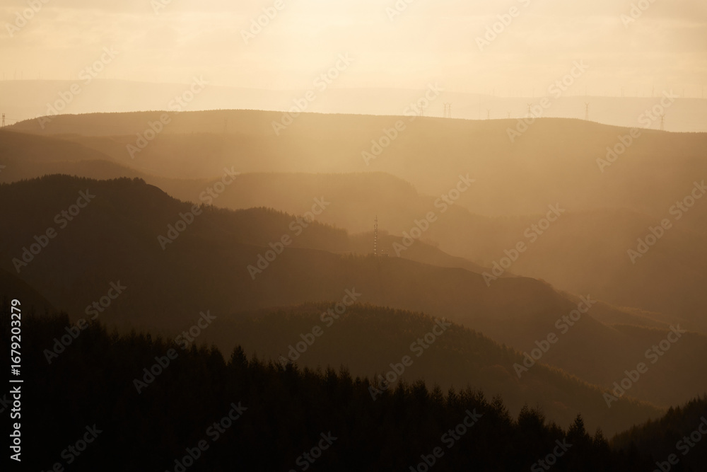 Obraz premium Sunlit mountains and hazy light effects at sunrise in Ulan Butong, China