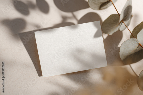 Blank business card on soft surface with eucalyptus leaves 