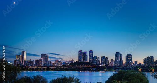 The splendid night view of the Han River in Seoul skyline and cityscape, South Korea, with the first quarter moon after sunset (Panorama, High Resolution)