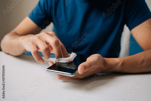 Canvas Print Close-up of male hands carefully cleaning smartphone screen with wet wipe and alcohol pad, wiping away dirt and fingerprints for optimal device hygiene