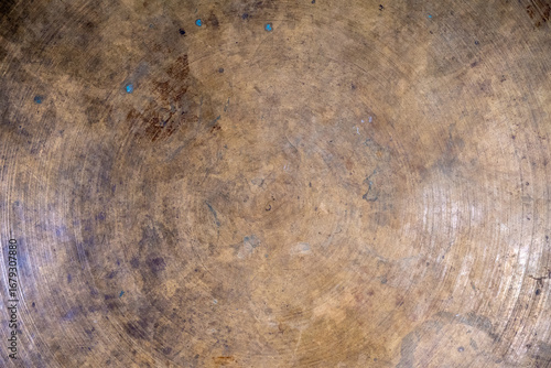 Close-up of an aged, textured brass surface with circular patterns.