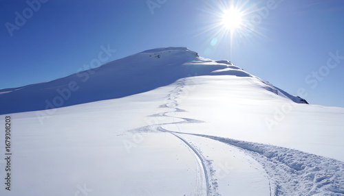 Sunlight illuminates the snow-covered peaks of a vast mountain landscape, creating a stunning panorama for back country skiing