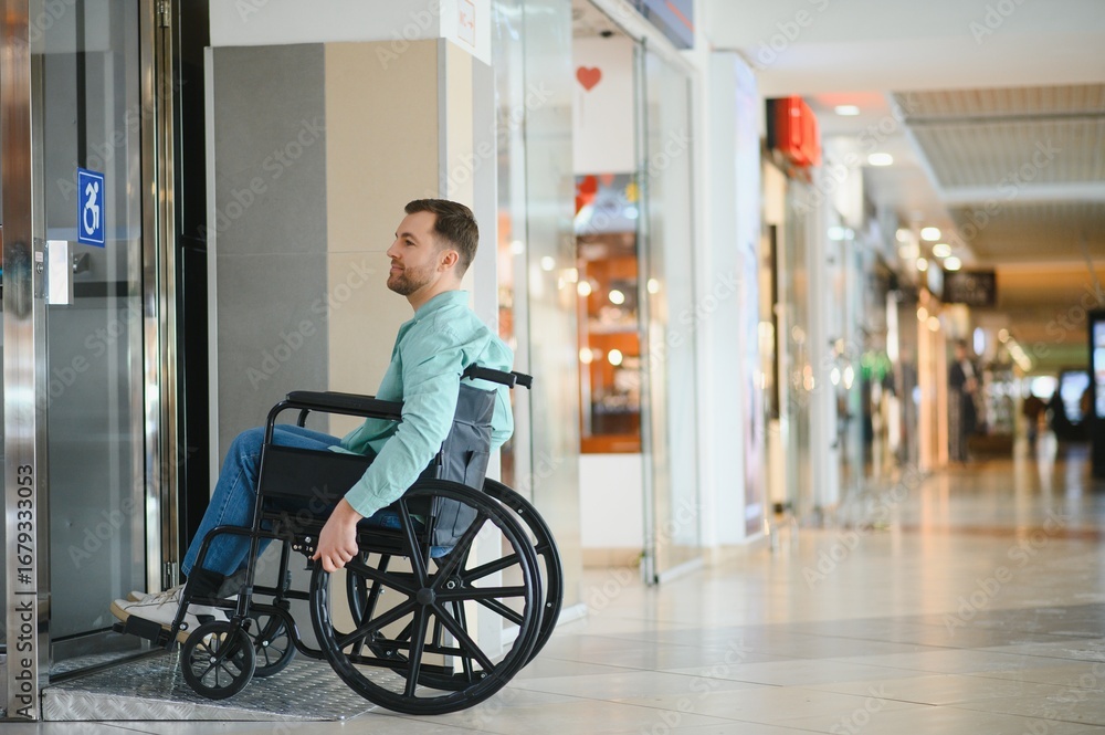 Obraz premium Man in wheelchair exiting elevator in shopping mall