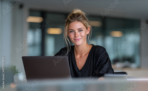 Young professional woman working on laptop in modern office, smiling, business workspace, remote work concept, productivity, daylight, 4K, realistic - businesswoman working in office