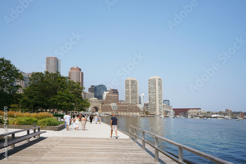 People stroll along the harborwalk in the Seaport area of Boston