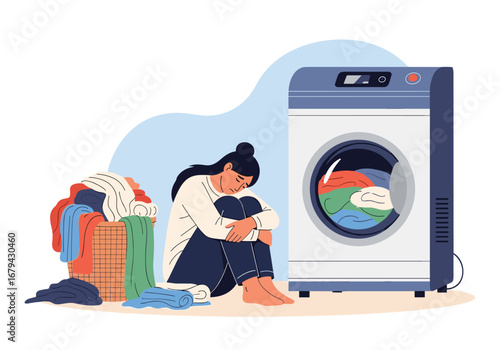 Woman sitting beside a laundry basket and washing machine feeling depressed and overwhelmed by chores