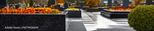 Polished granite tombstones in a tidy and well-kept cemetery with lush greenery. A tranquil and respectful place for remembrance.