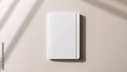 Minimalist flat lay of a blank white hardcover notebook on a neutral surface with elegant shadow play. Concept for branding, notes, or personal planning