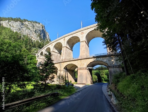 Summer landscape featuring the iconic Semmering railway viaduct in Austria, photographed on a bright sunny day against a clear blue sky. 