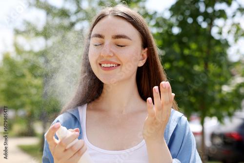 Wallpaper Mural Smiling woman spraying thermal water from bottle outdoors Torontodigital.ca