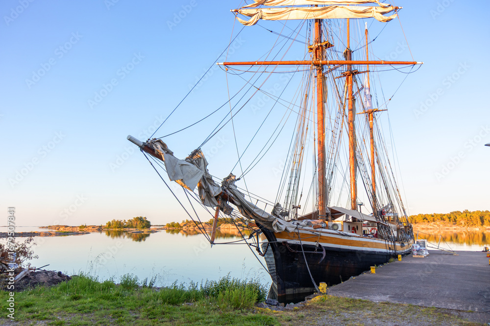 Obraz premium Vintage wooden boat moored at a pier in Finland, Baltic Sea. Rustic maritime scene, traditional craftsmanship, peaceful harbor, connection with northern coastal culture