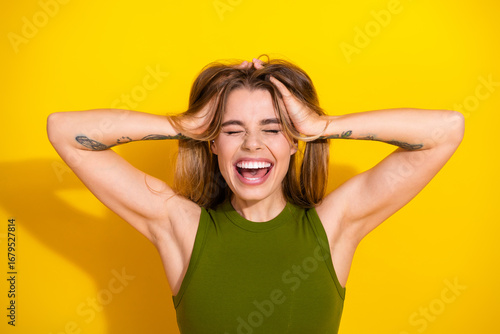 Obraz na plátne Joyful young woman in a green casual top posing against a vibrant yellow backgro